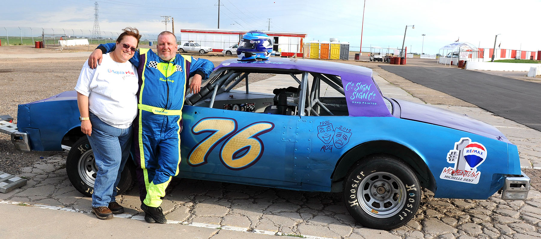 A couple standing next to a race car.